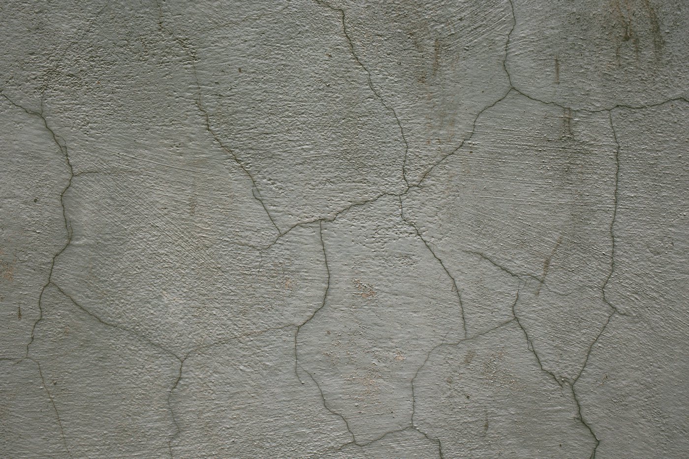 Hairline map cracking across a weathered gray concrete wall