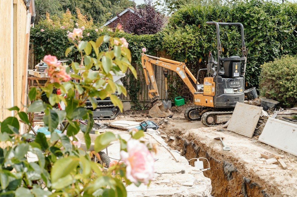 A mini excavator digging a trench along a house foundation